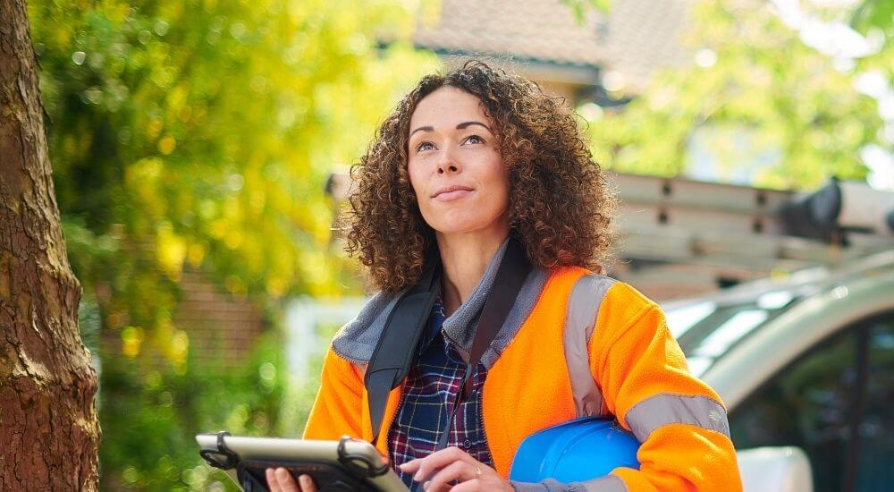 Female property restorer in high-vis jacket with blue hard hat tucked under her arm